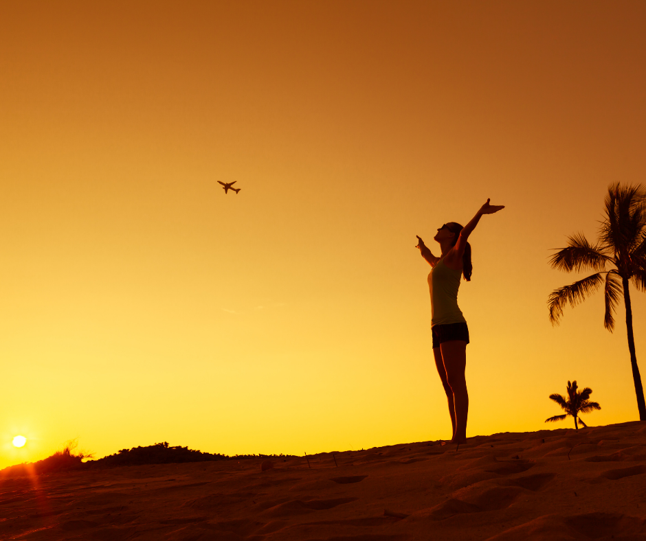 Femme regardant le ciel sur une plage au coucher du soleil (sentiment de liberté)